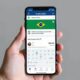 Aposentado usando celular para solicitar reembolso de desconto indevido no INSS via aplicativo Meu INSS